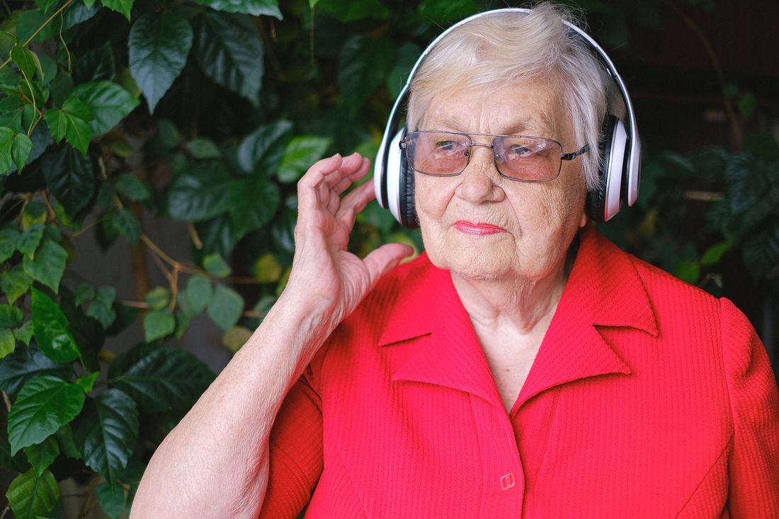 A resident enjoying music with headphones in her community garden