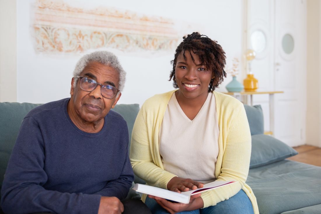 A caregiver reading together with an older man at home